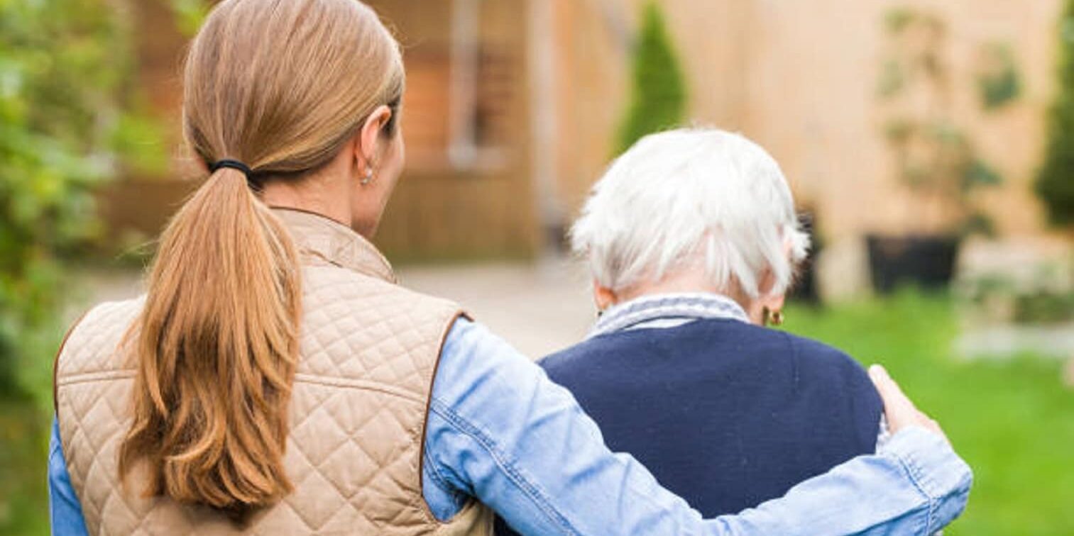 Young carer walking with the elderly woman in the park